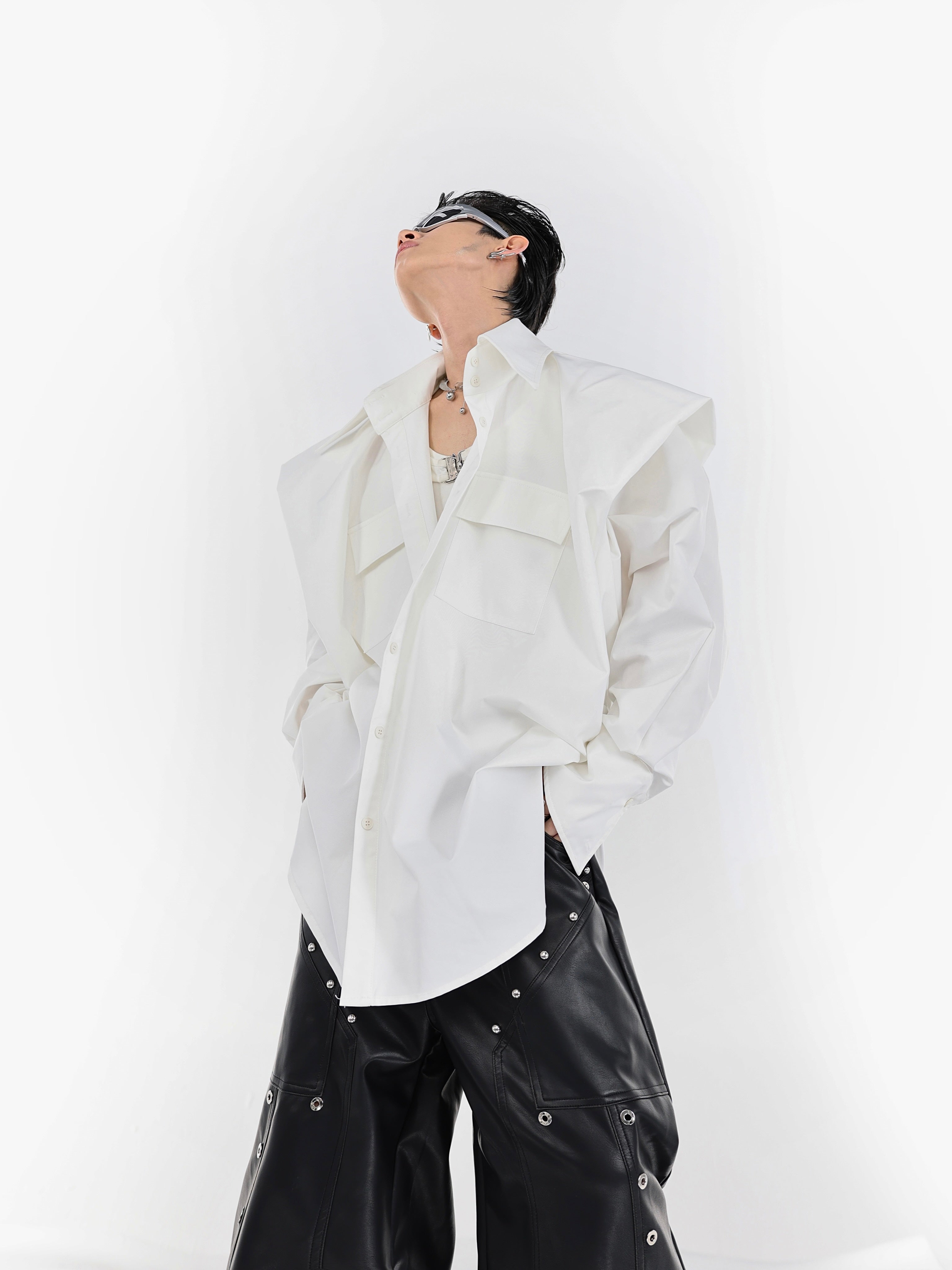 Close-up detail of the deconstructed pleated shirt's enhanced wide shoulder construction and premium fabric texture