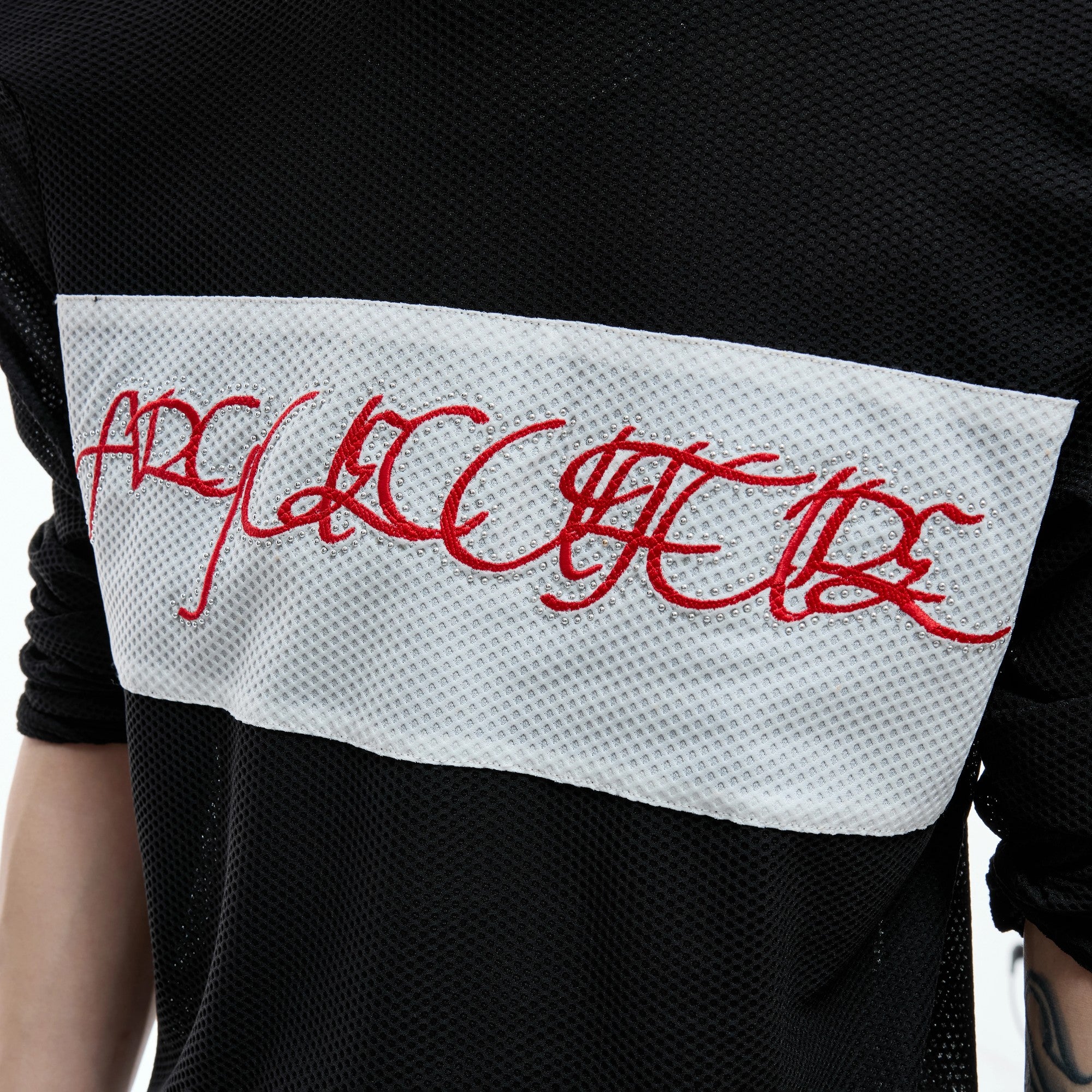 Close up of high-density red script embroidery on mesh fabric