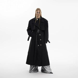 Model wearing a black oversized deconstructed trench coat with padded shoulders.