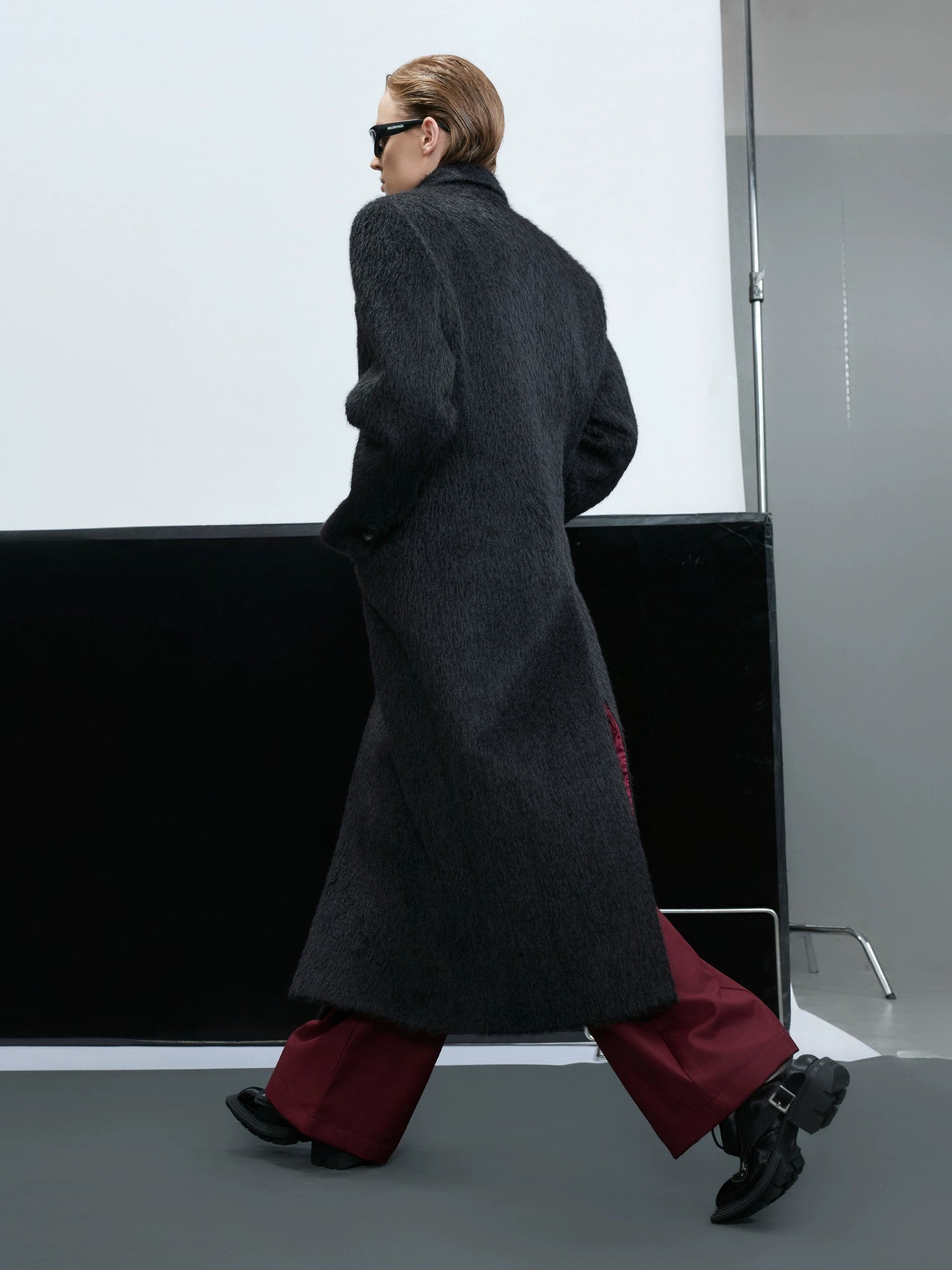 Model wearing a long black alpaca wool coat in an urban street setting