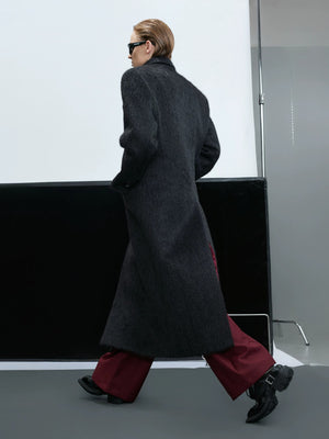Model wearing a long black alpaca wool coat in an urban street setting