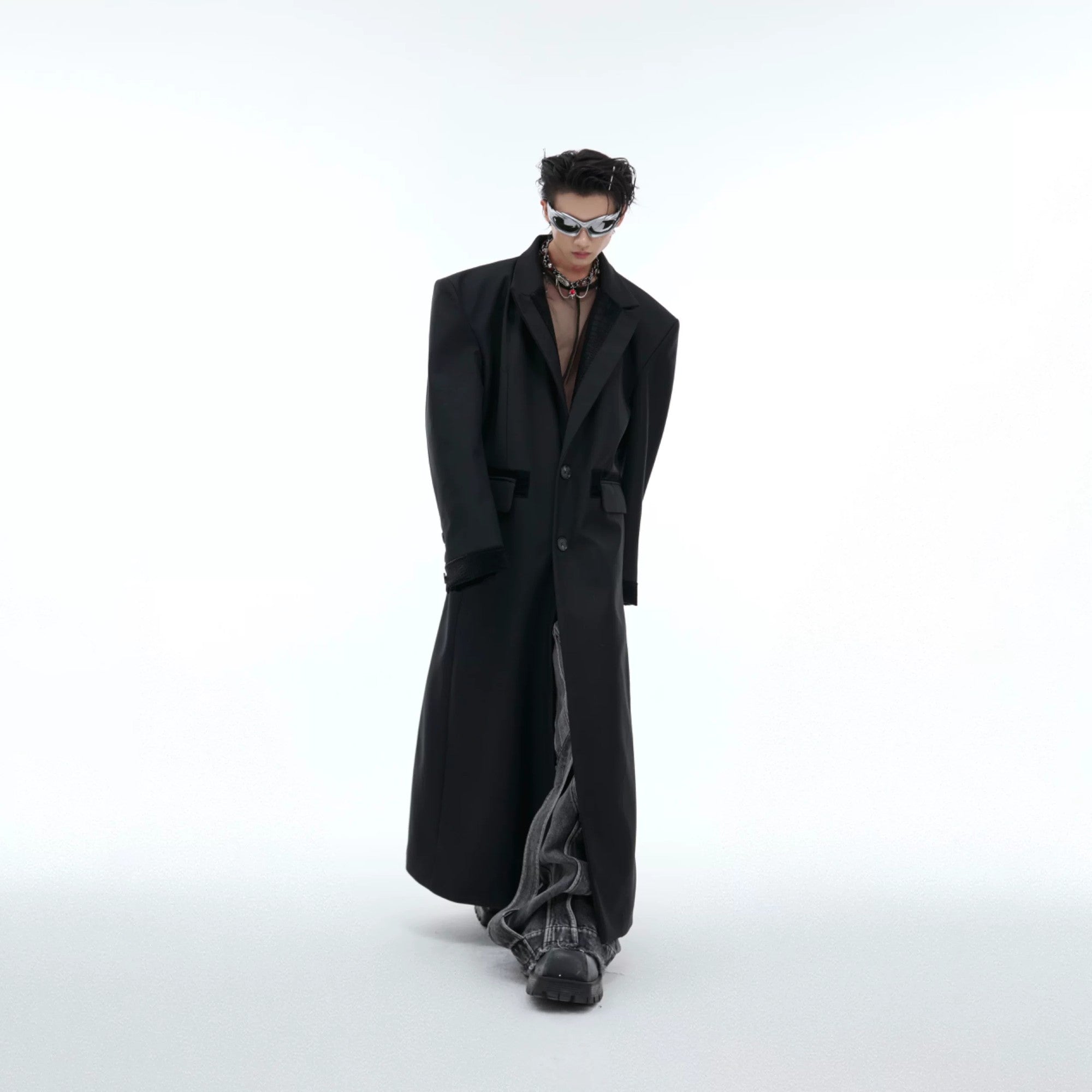 Front view of an oversized black long coat with PU leather splicing and padded shoulders.