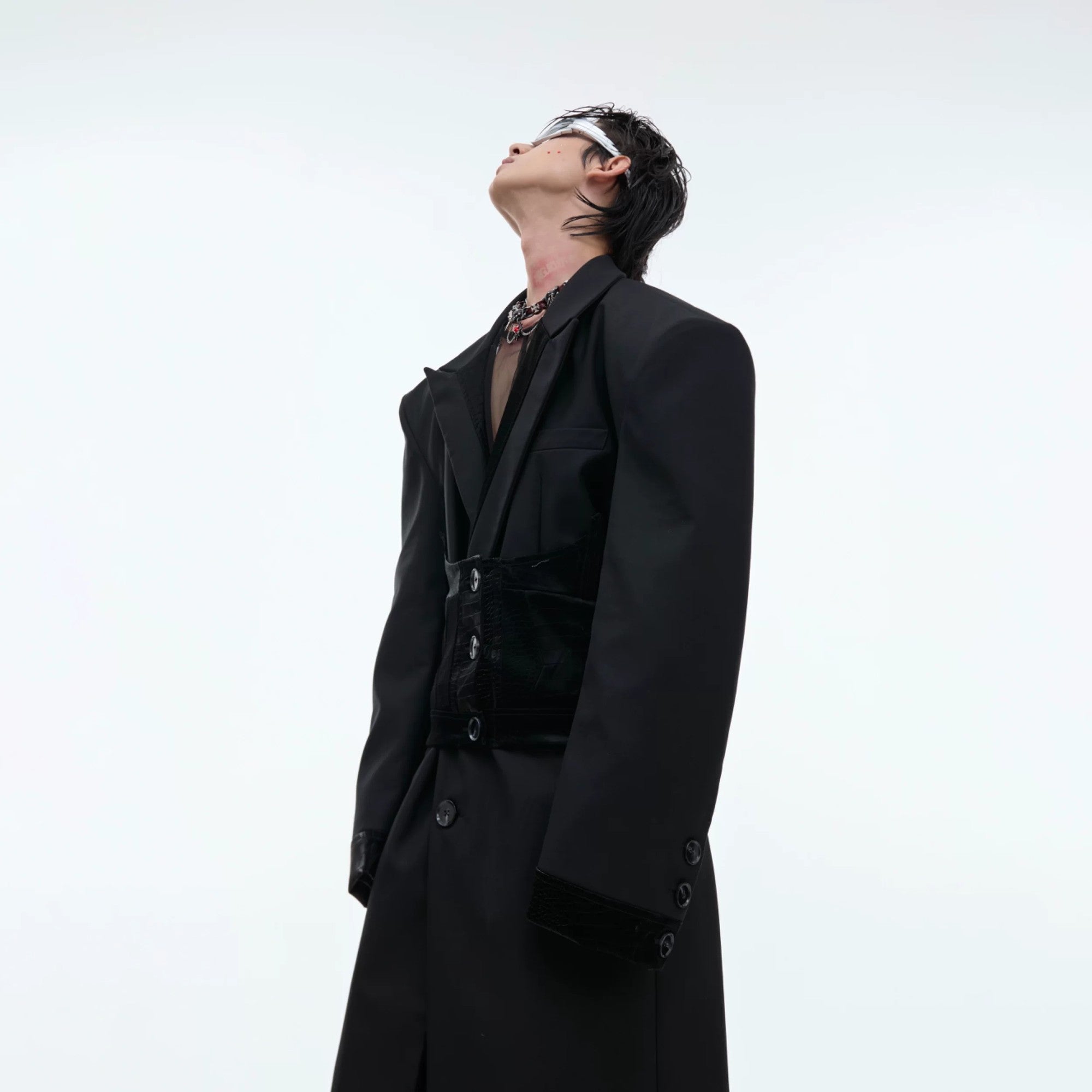 Side view showing the structured silhouette and long length of the black coat.