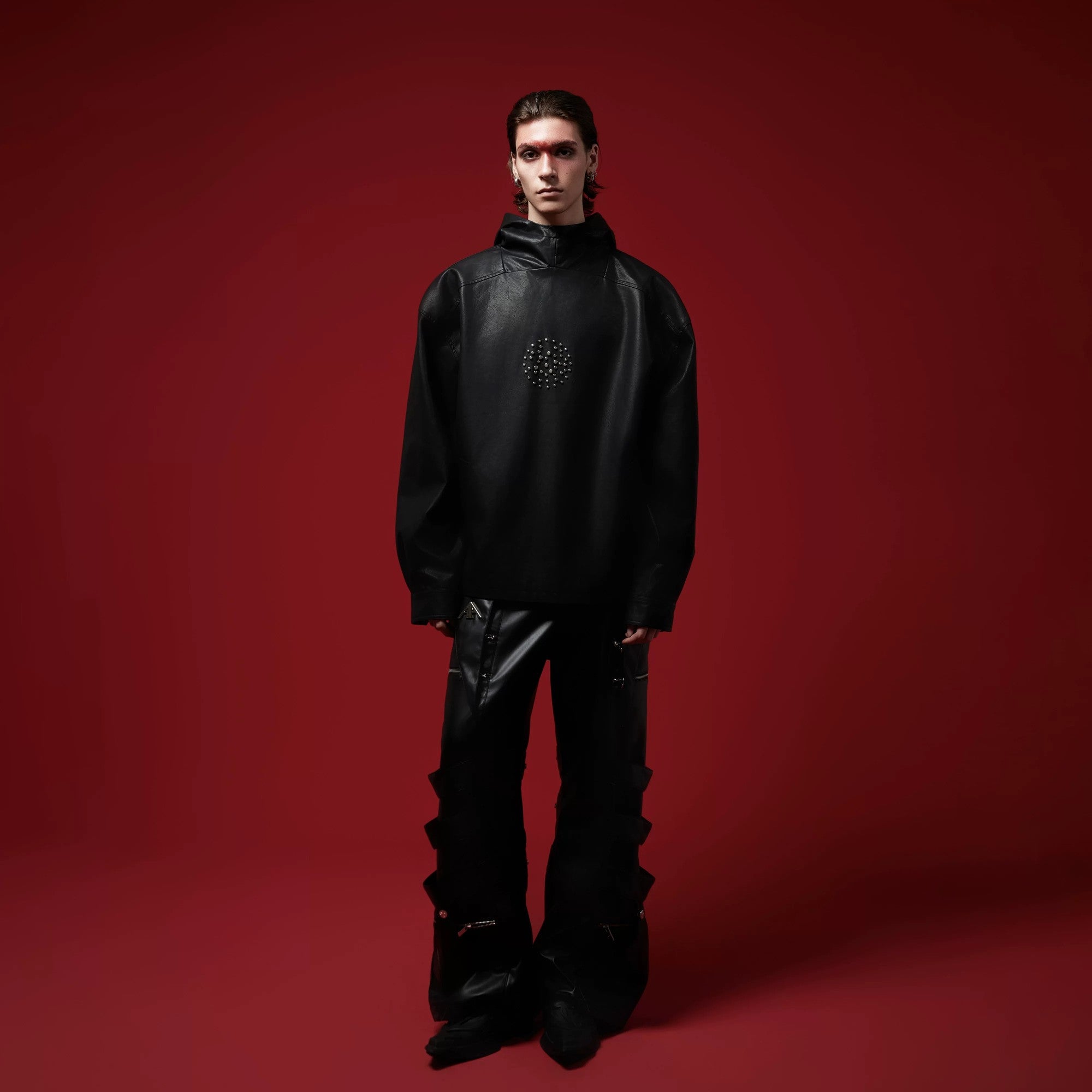 Model wearing a baggy black leather hoodie in a street setting