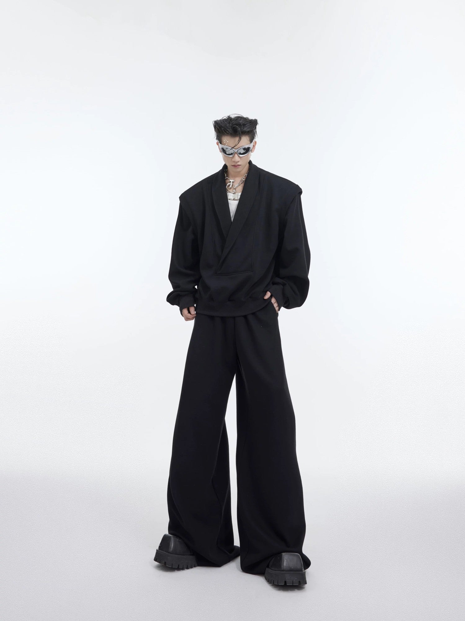 Model wearing black oversized V-neck sweatshirt with metal accents streetwear