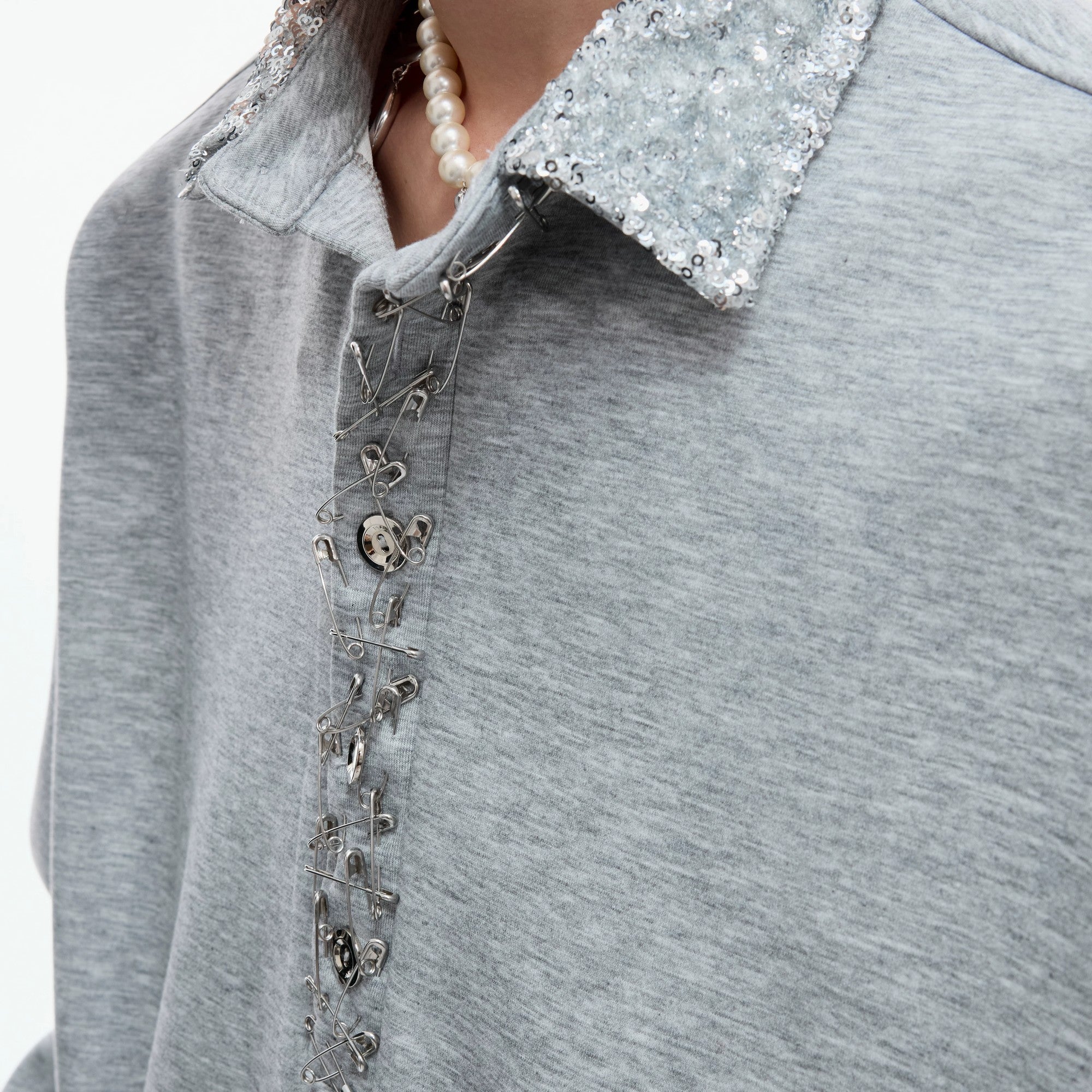 Model wearing a white sequin polo sweatshirt in an urban setting