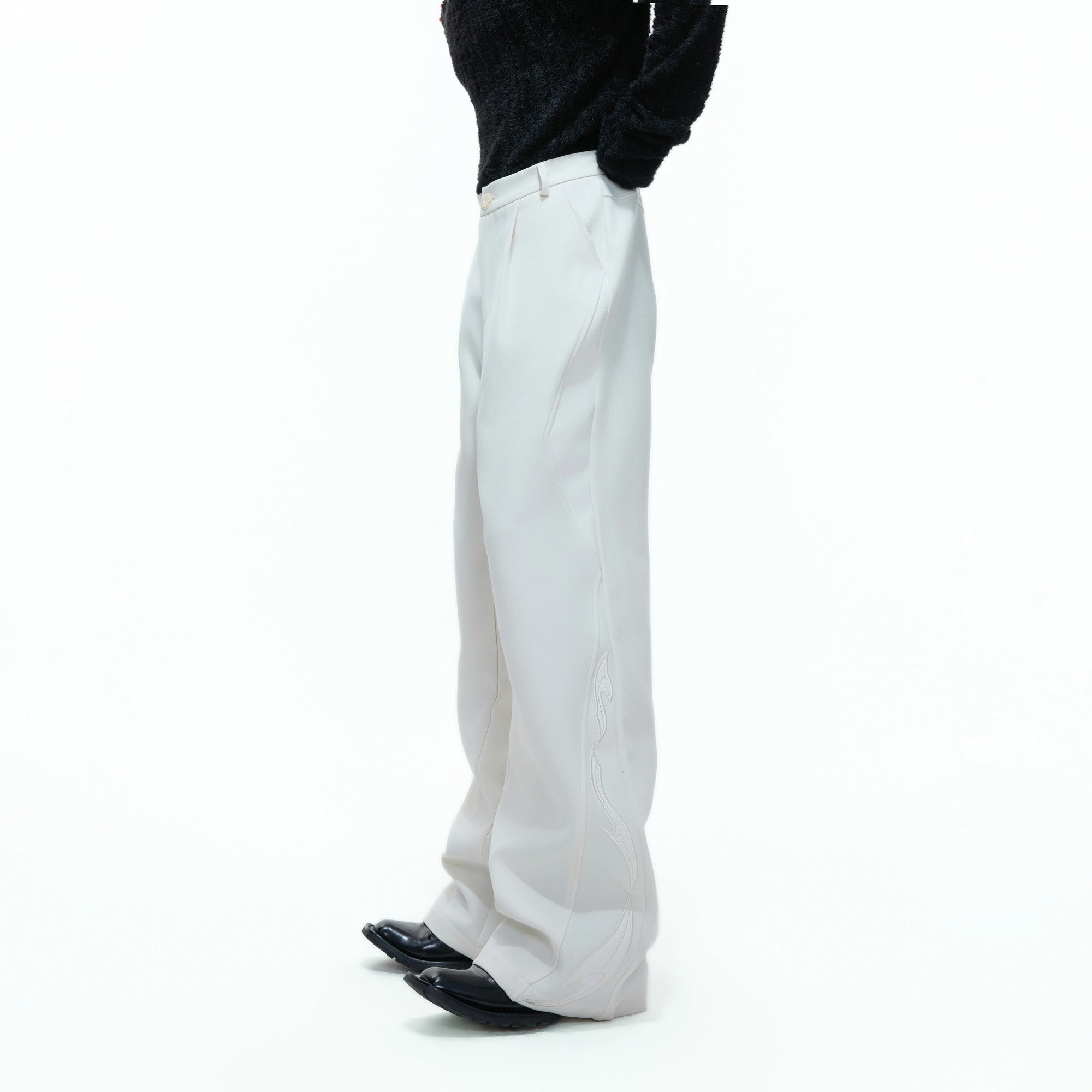 Model wearing black wide leg deconstructed trousers in an urban street setting