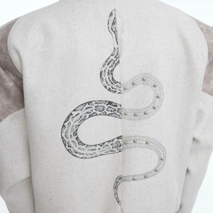 Back view of a cropped jacket with intricate serpent embroidery.
