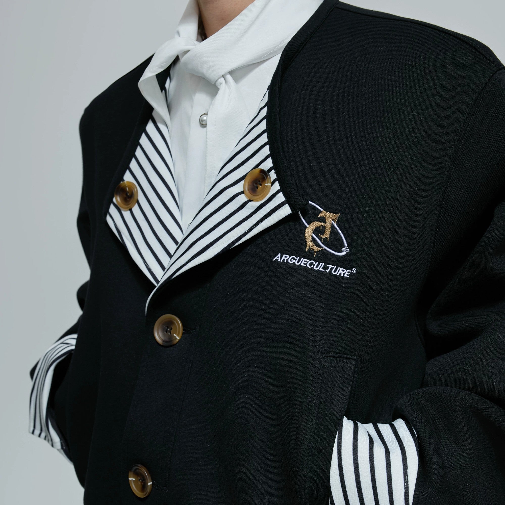 Unisex model wearing a black striped faux two-piece jacket